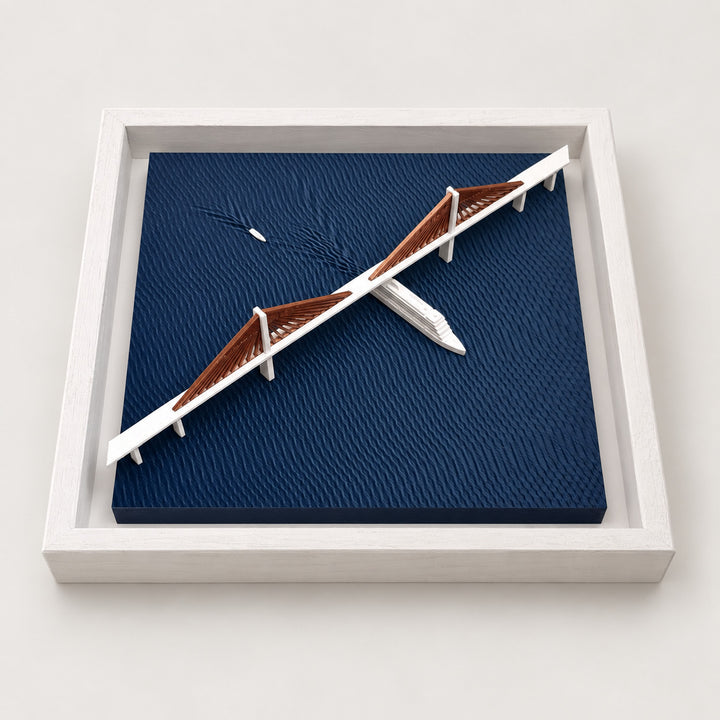 Angled view of Sunshine Skyway Bridge wall art with copper-colored cables, white boats and navy textured water in a white frame.